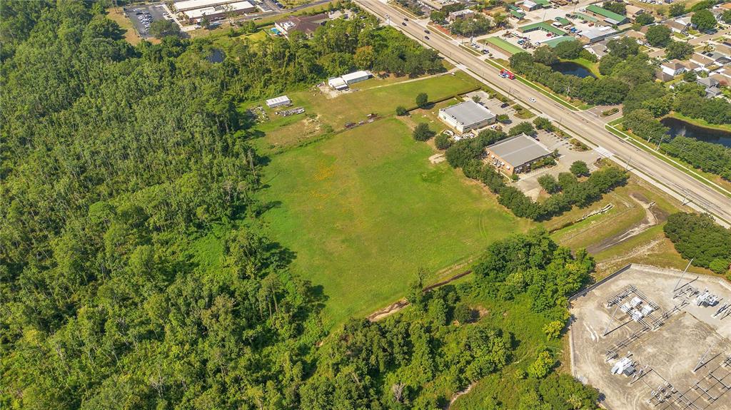 An aerial view shows two commercial buildings, parking lots, and large open fields near woods — ROCK SPRINGS ROAD, APOPKA, FL