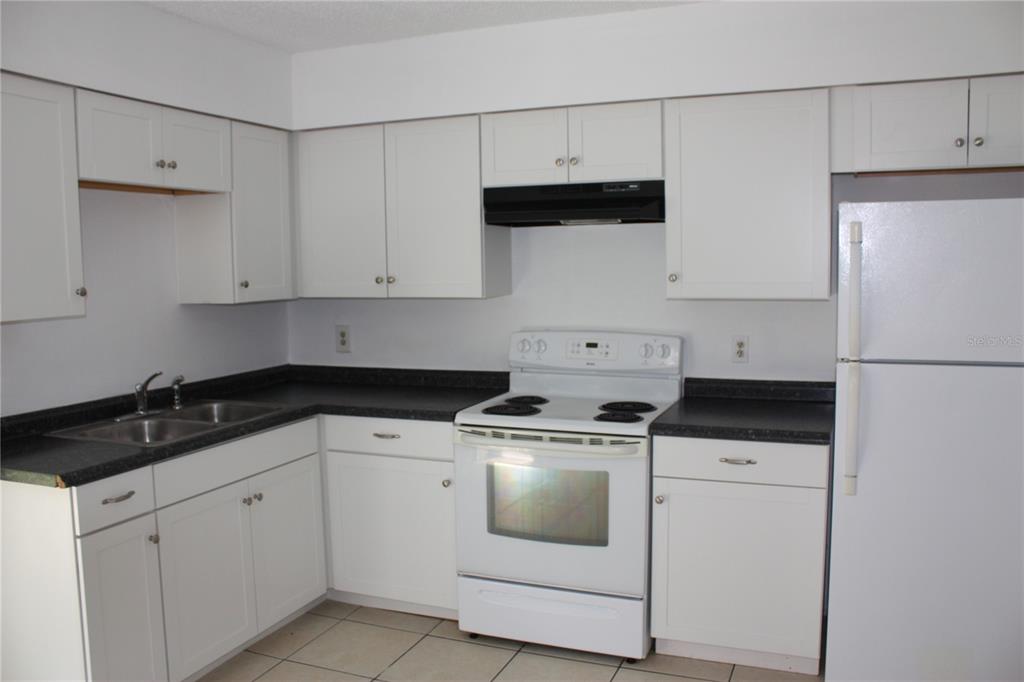 A kitchen with white cabinets, black countertops, a white stove, and a white refrigerator — 7965 W FERN PLACE, HOMOSASSA, FL