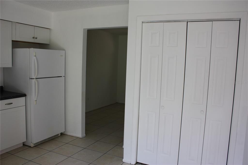 A kitchen features white cabinets, a white refrigerator, tiled floors, and a white closet door — 7965 W FERN PLACE, HOMOSASSA, FL