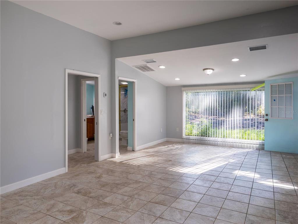 A room with light blue walls, tile flooring, two doorways, and a large window — 13117 N COUNTY ROAD 225, GAINESVILLE, FL