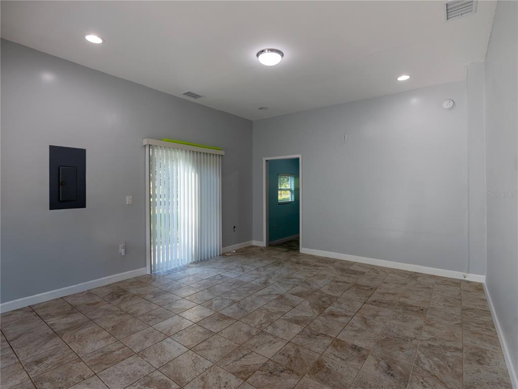 An empty room features light gray walls, tile flooring, recessed lighting, and a sliding glass door — 13117 N COUNTY ROAD 225, GAINESVILLE, FL