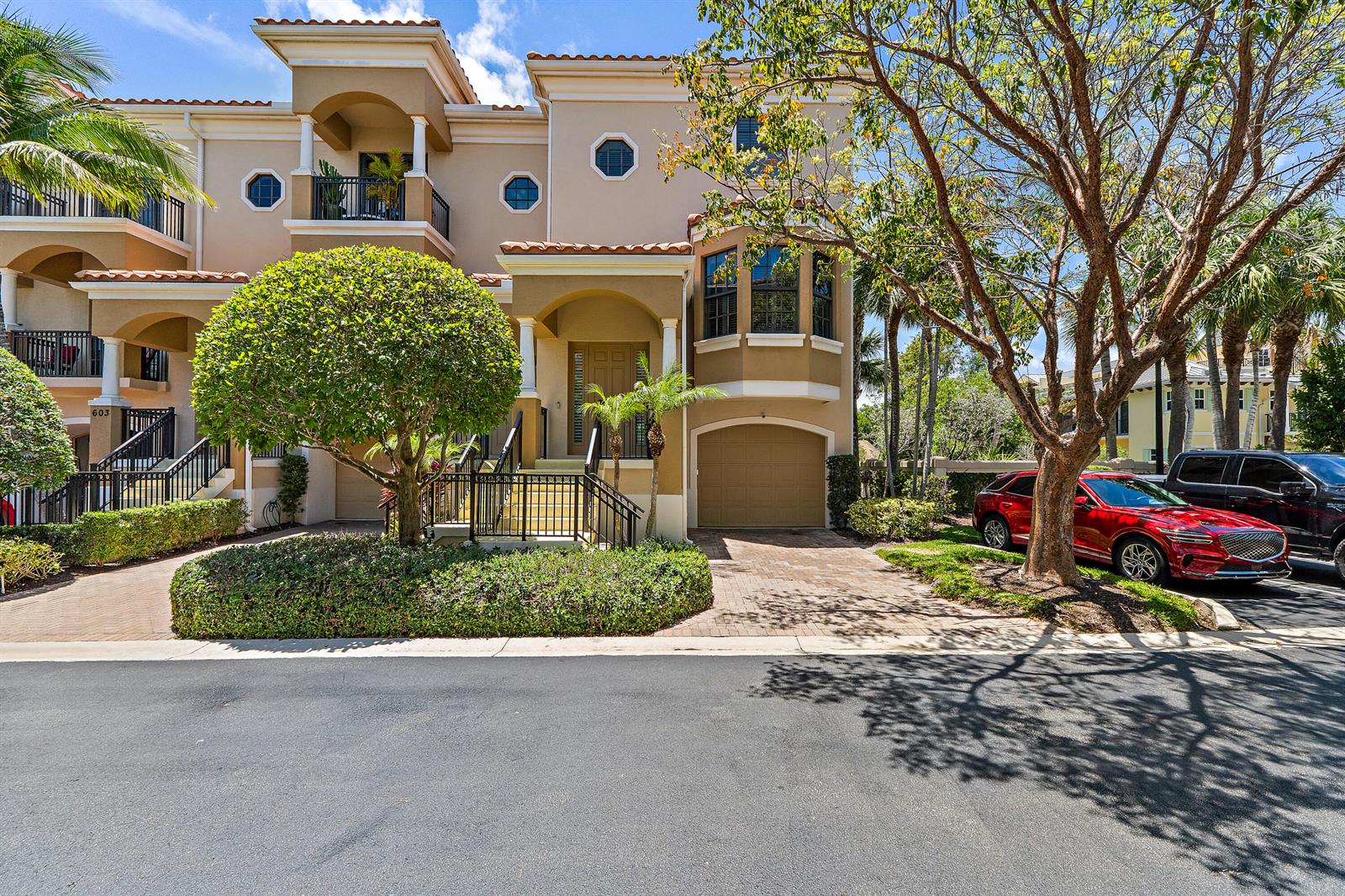 A multi-story tan townhouse with a garage, front stairs, and a paved driveway — 605 Del Sol Circle, Tequesta FL 33469, TEQUESTA, FL
