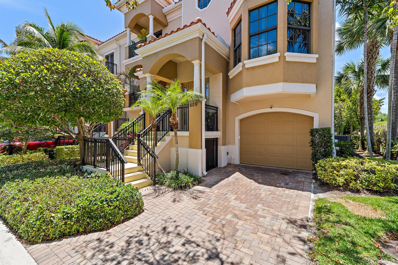 A multi-story tan townhouse with a brick driveway, a garage, and an elevated front entrance — 605 Del Sol Circle, Tequesta FL 33469, TEQUESTA, FL