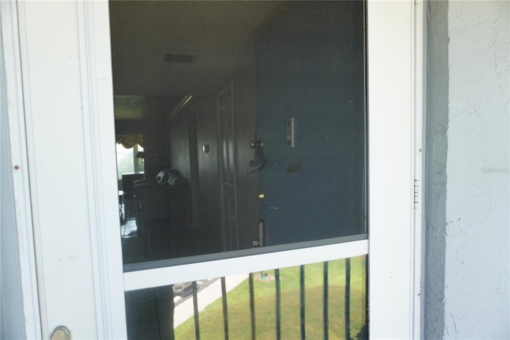 A view through a screen door looking into a dimly lit living room — 333 LAKE HOWARD DRIVE NW UNIT 303A, WINTER HAVEN, FL