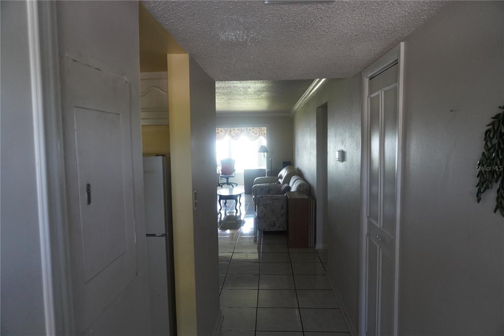 A hallway with tiled floors leads to a living room with a bright window — 333 LAKE HOWARD DRIVE NW UNIT 303A, WINTER HAVEN, FL