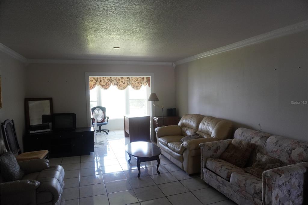 A living room with tiled floors, two sofas, a coffee table, and a windowed alcove — 333 LAKE HOWARD DRIVE NW UNIT 303A, WINTER HAVEN, FL