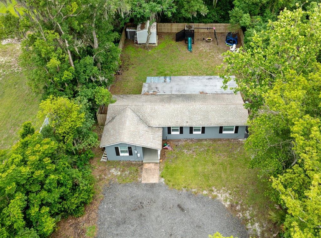 An aerial view shows a gray single-story house with a gravel driveway and fenced backyard — 580 LAKEVIEW AVENUE, ORANGE CITY, FL