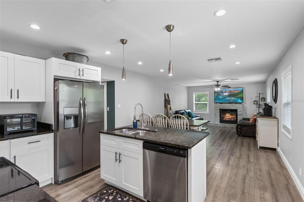 A kitchen with white cabinets and dark countertops opens into a living room with a fireplace — 580 LAKEVIEW AVENUE, ORANGE CITY, FL