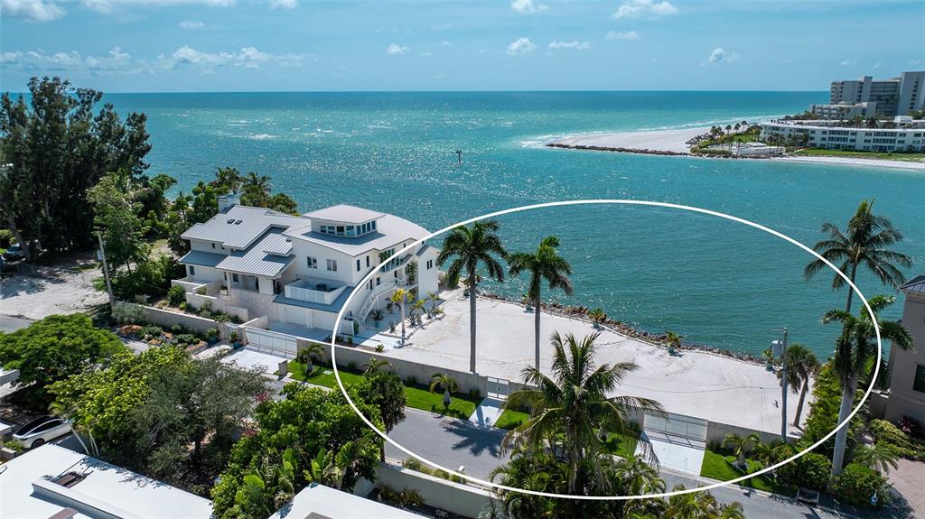 An aerial view shows a waterfront property with a white house and a sandy yard — 1215 WESTWAY DRIVE, SARASOTA, FL