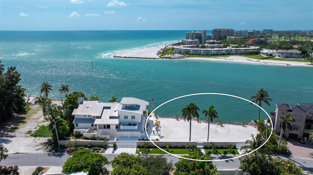 An aerial view shows a waterfront property with a large sandy yard and palm trees — 1215 WESTWAY DRIVE, SARASOTA, FL