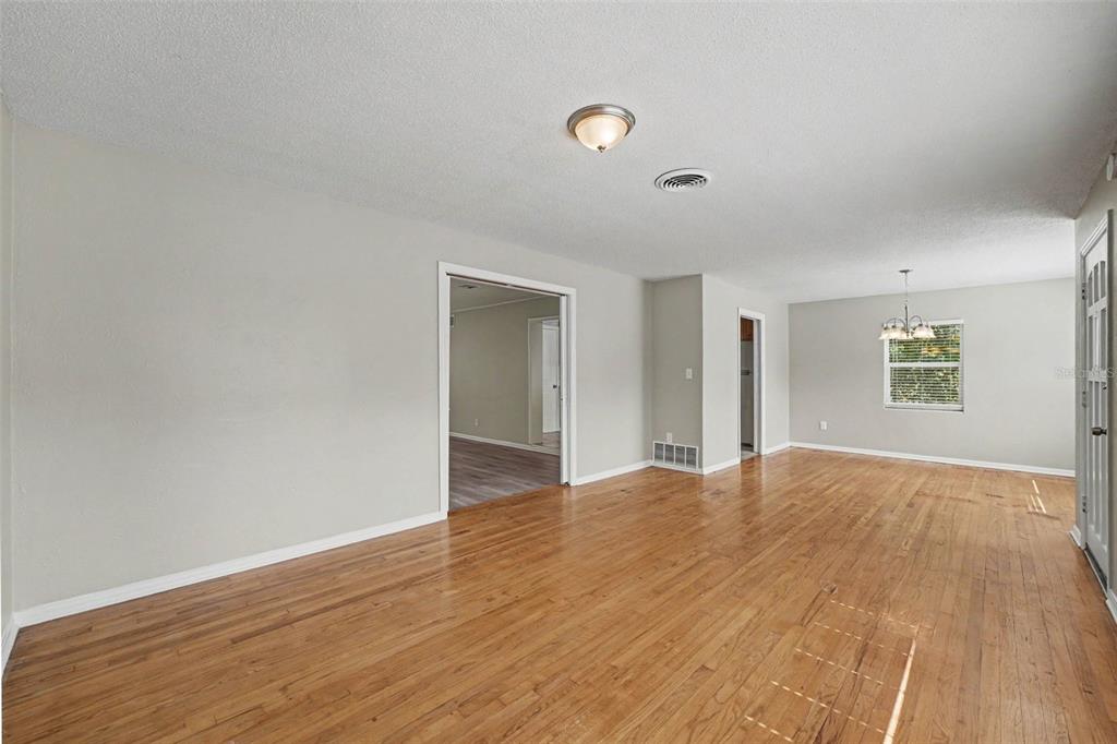 An empty living room features light-colored walls, hardwood floors, and a ceiling light fixture — 2935 WOODLAND HILLS AVENUE, LAKELAND, FL