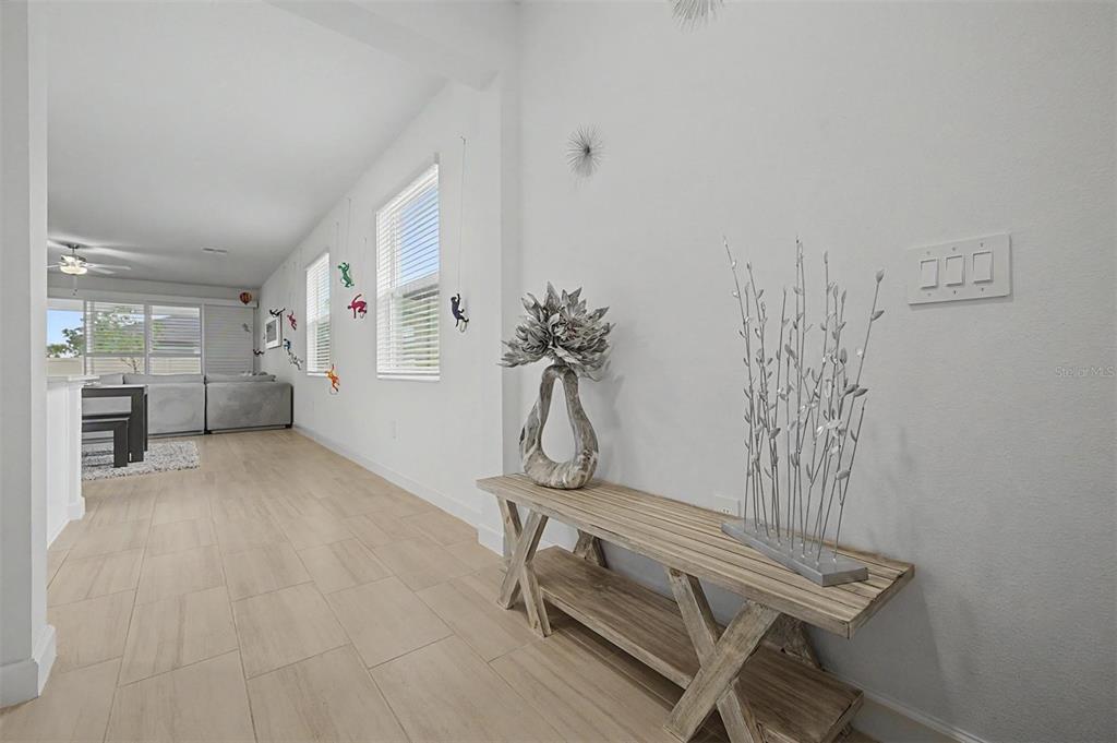 A hallway features light wood-look tile flooring, a rustic wooden console table, and white walls — 10733 TUPPER CAY DRIVE, SAN ANTONIO, FL