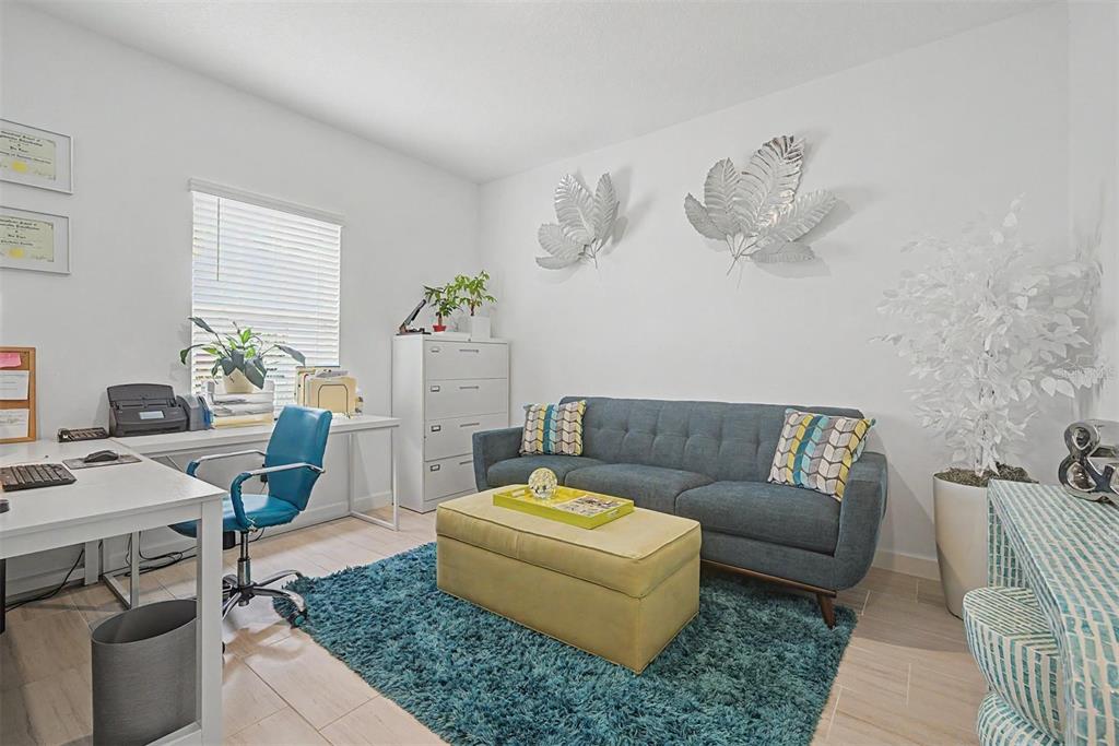 A home office features a desk, a blue sofa, a yellow ottoman, and a rug — 10733 TUPPER CAY DRIVE, SAN ANTONIO, FL