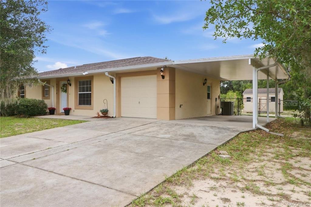 A single-story house with a beige exterior, a one-car garage, and an attached carport — 9734 E GRANADA COURT, INVERNESS, FL