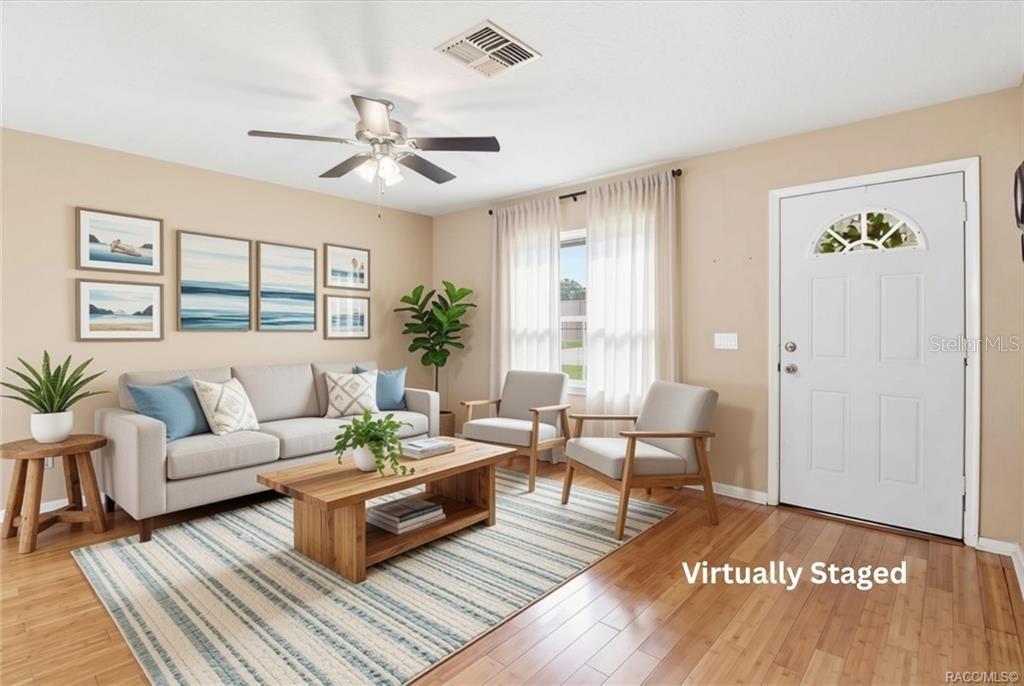 This virtually staged living room features a sofa, two armchairs, a coffee table, and hardwood floors — 9734 E GRANADA COURT, INVERNESS, FL