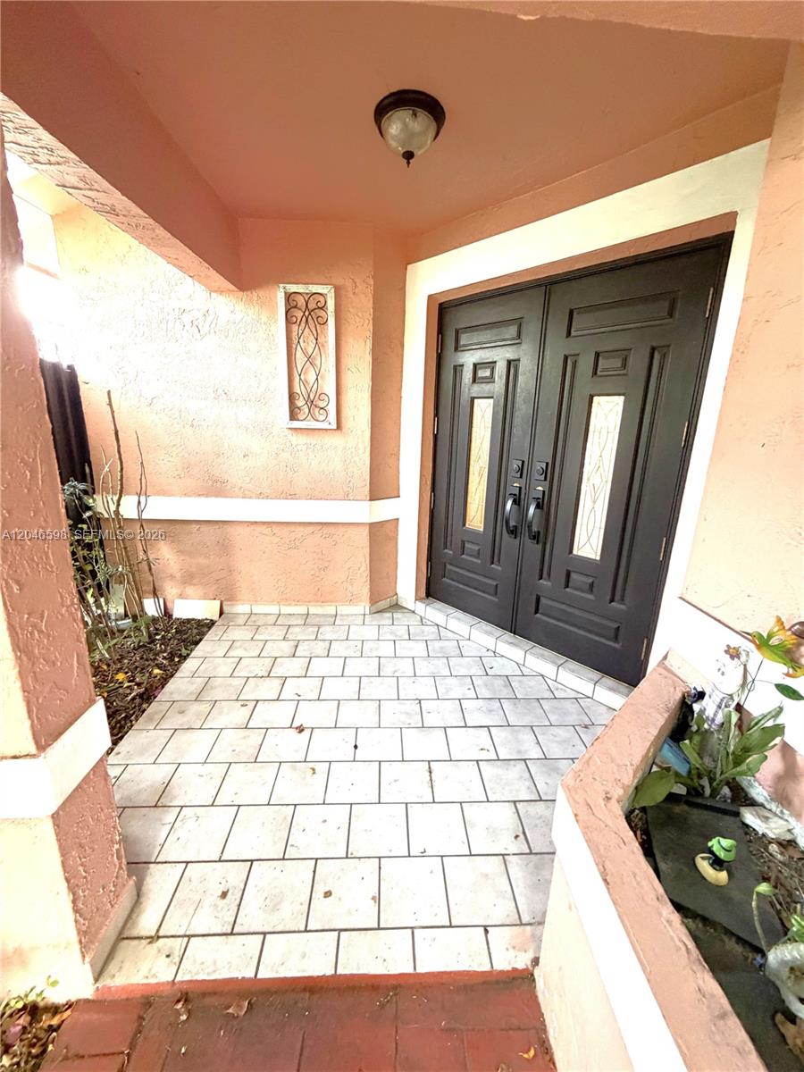 A covered entryway features a tiled floor, peach-colored walls, and dark double front doors — 14225 SW 55th St, Miami FL 33175, MIAMI, FL