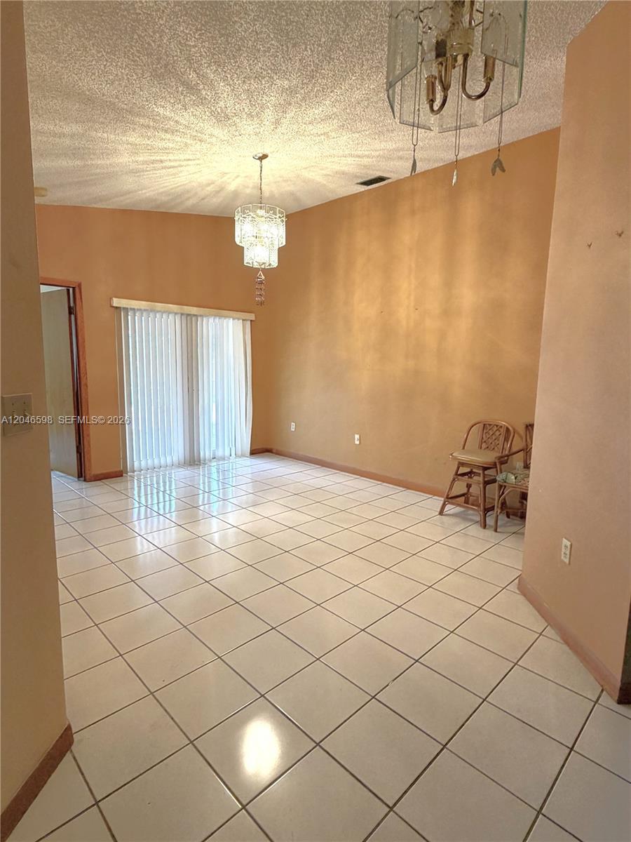 A dining room features tan walls, white tile flooring, and two crystal chandeliers — 14225 SW 55th St, Miami FL 33175, MIAMI, FL