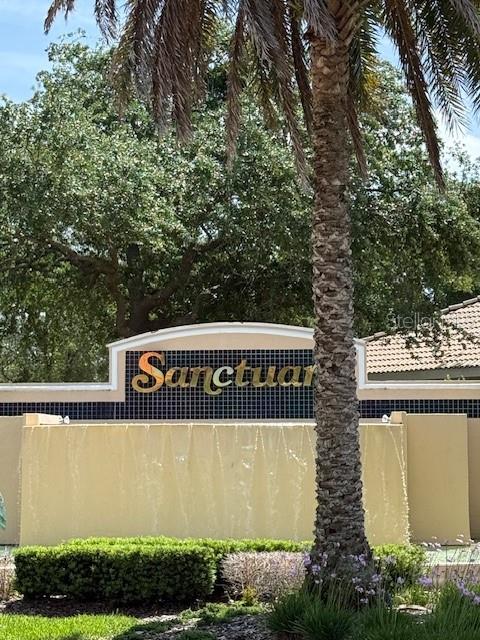 A palm tree stands in front of a water feature with a sign reading Sanctuary — 75 OLD OAK DRIVE S, PALM COAST, FL