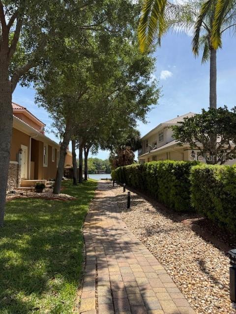 A paved walkway leads between two houses toward a body of water under a blue sky — 75 OLD OAK DRIVE S, PALM COAST, FL