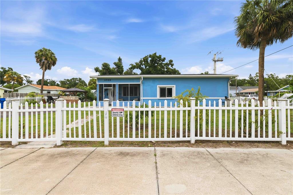 A blue single-story house with a white picket fence stands behind a concrete driveway — 3706 OLD BRADENTON ROAD, SARASOTA, FL