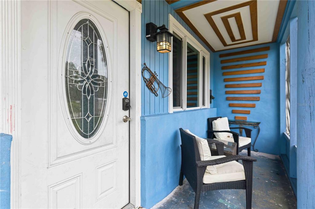 A blue-painted front porch features two wicker chairs, a trumpet wall decoration, and a door — 3706 OLD BRADENTON ROAD, SARASOTA, FL