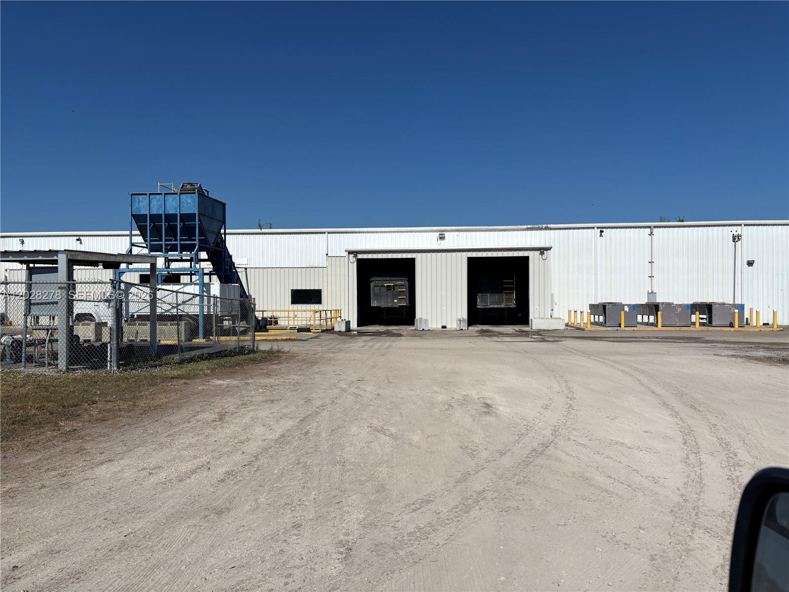 A large industrial warehouse building with two open loading bays and a blue hopper — 15877 E SR 80, Clewiston FL 33440, CLEWISTON, FL