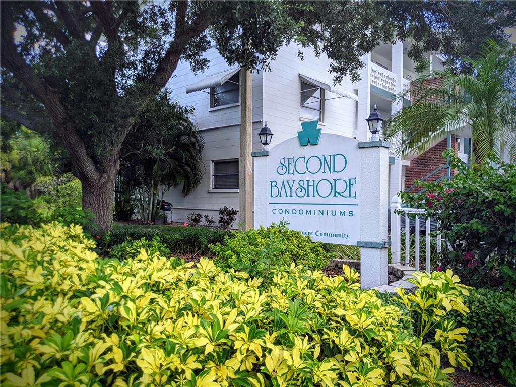 A sign for Second Bay Shore Condominiums stands in front of a white residential building — 5864 WELCOME ROAD UNIT J-26, BRADENTON, FL