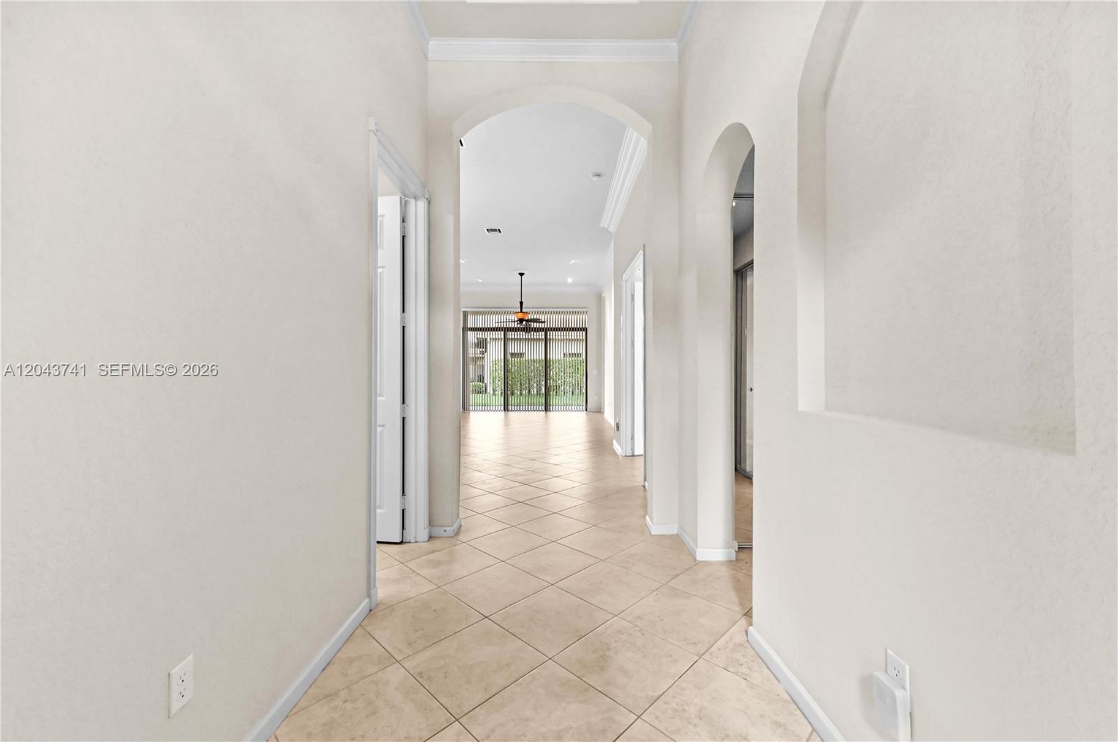A tiled hallway leads through an arched opening toward a room with large glass doors — 6823 Fabiano Cir, Boynton Beach FL 33437, BOYNTON BEACH, FL