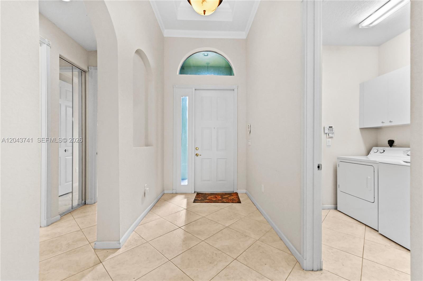 An entryway with tile flooring leads to a front door and an adjacent laundry room — 6823 Fabiano Cir, Boynton Beach FL 33437, BOYNTON BEACH, FL