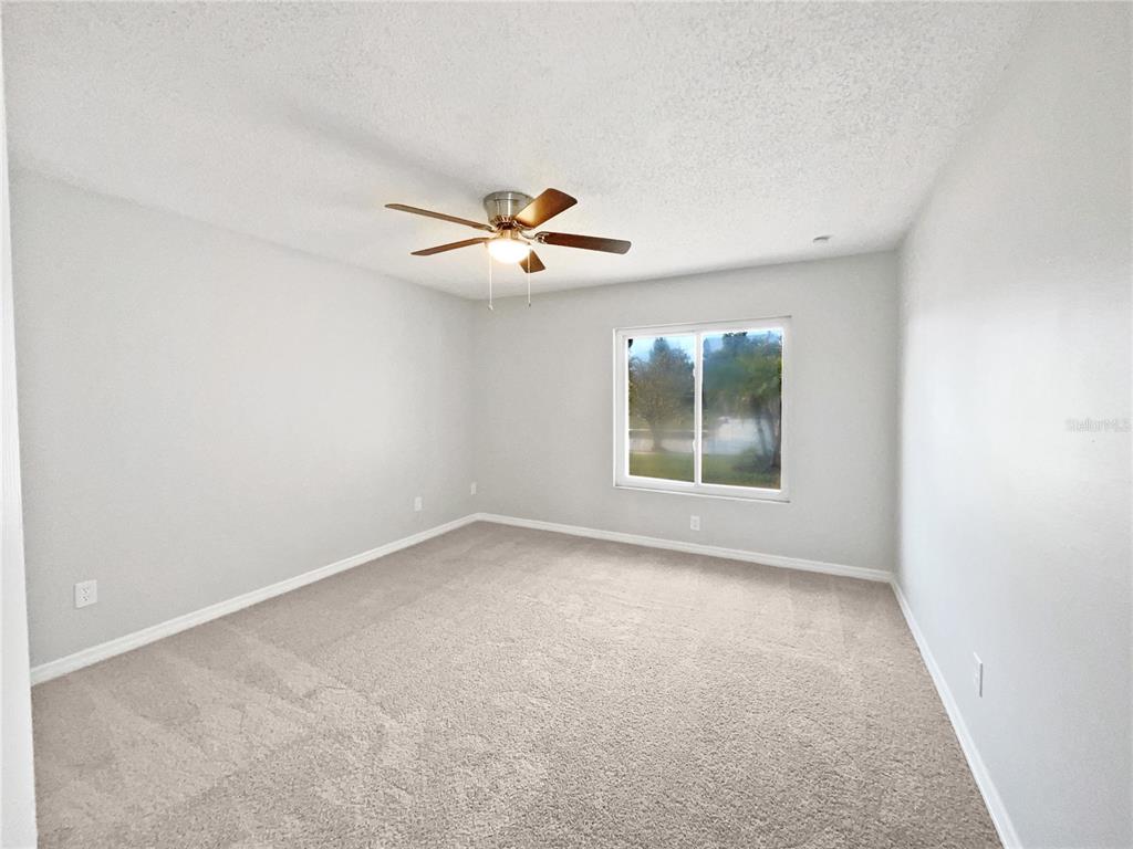 A bedroom with light gray walls, beige carpeting, a ceiling fan, and a single window — 831 HAULOVER DRIVE, ALTAMONTE SPRINGS, FL