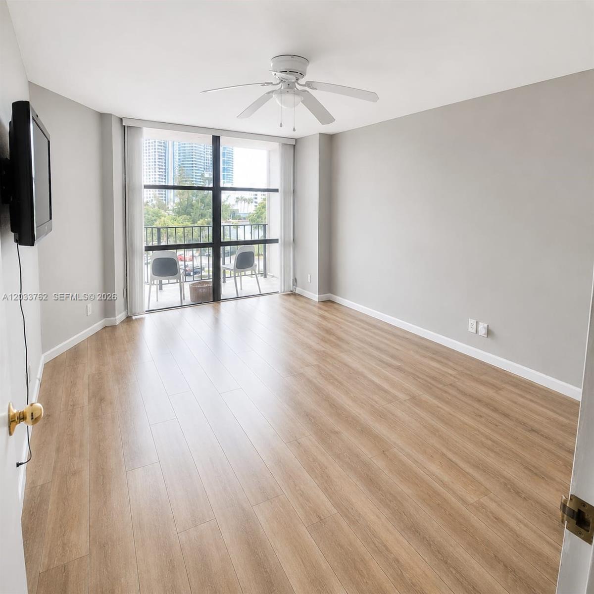 An empty room with light wood flooring, gray walls, a ceiling fan, and a balcony — 800 Parkview Dr # 512, Hallandale Beach FL 33009, HALLANDALE BEACH, FL
