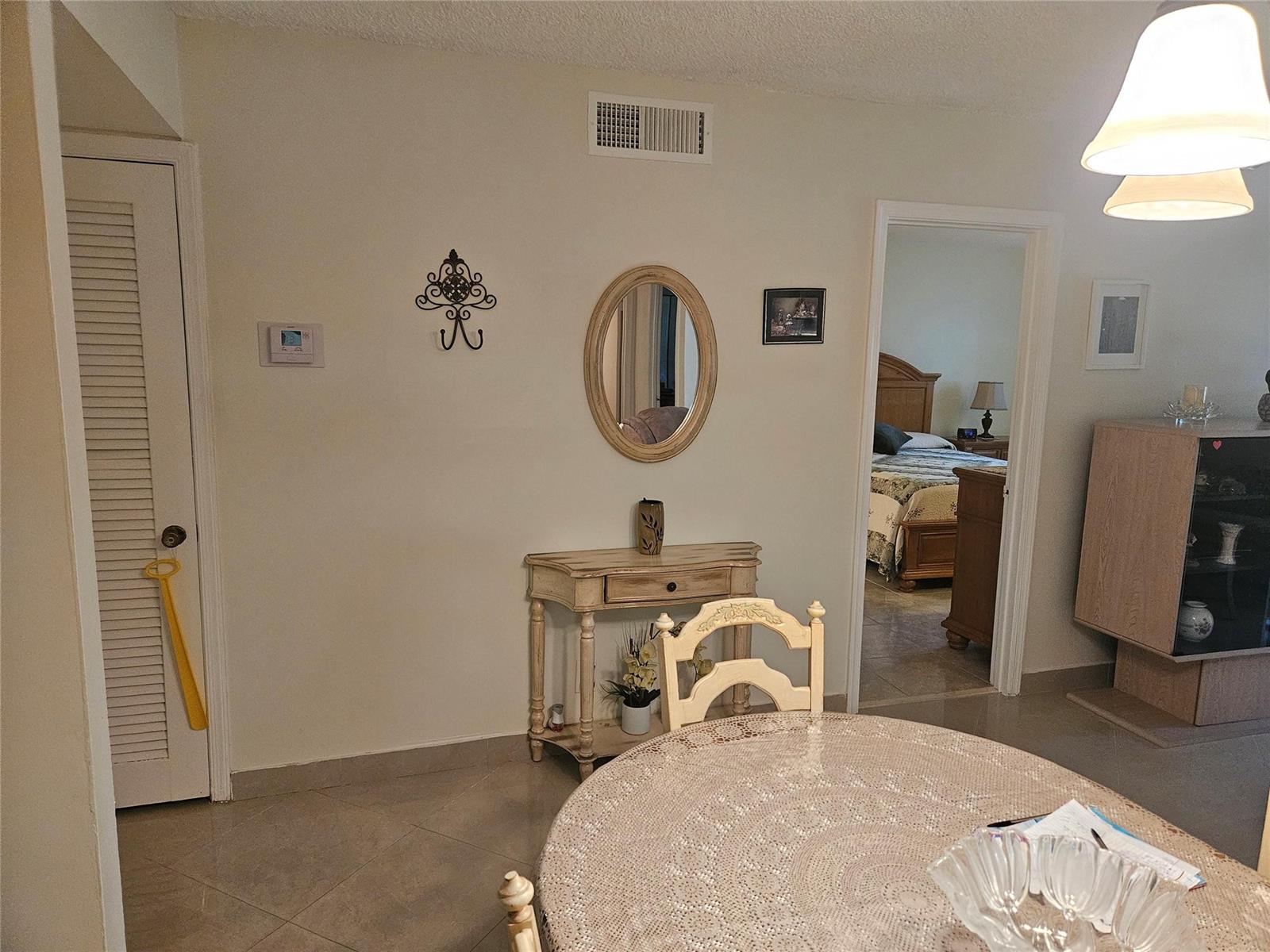 A dining area features a round table, a console table, and a doorway to a bedroom — 959 SE 2nd Avenue # 117, Deerfield Beach FL 33441, DEERFIELD BEACH, FL