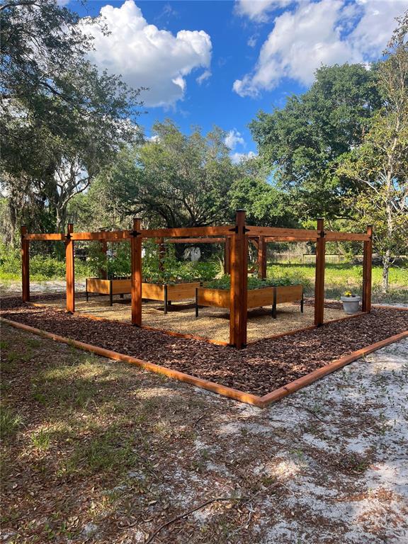 A fenced-in garden area features three raised wooden planter boxes on a bed of mulch — 11136 LORE WAY, ORLANDO, FL