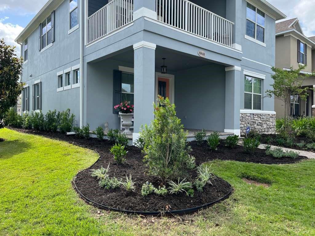 A two-story blue house with a covered front porch, balcony, and landscaped front yard — 11136 LORE WAY, ORLANDO, FL