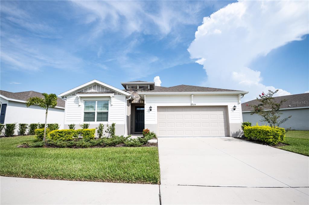 A single-story suburban house features white siding, a two-car garage, and a landscaped front yard — 13324 WATERLEAF GARDEN CIRCLE, RIVERVIEW, FL