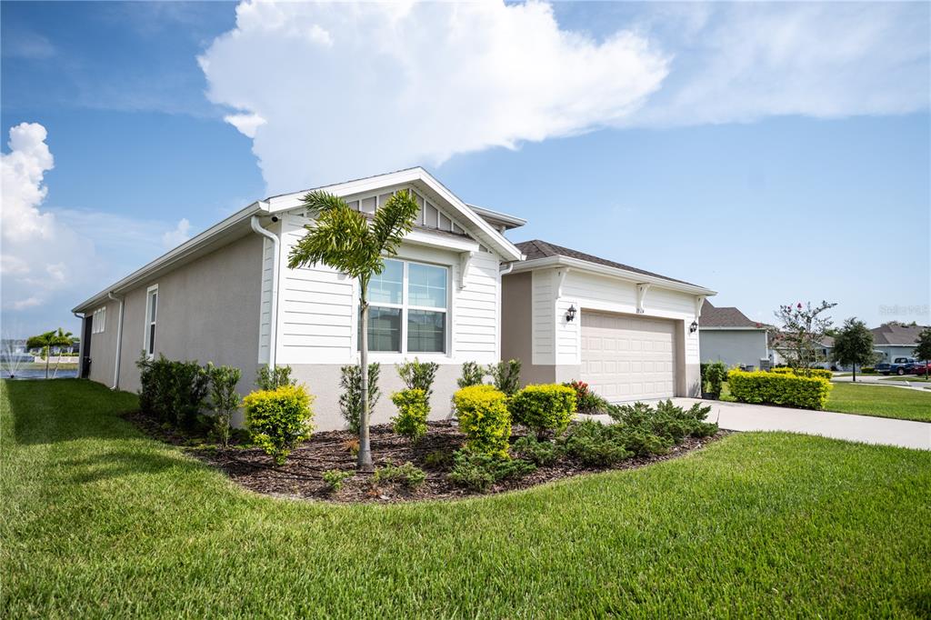 A single-story house with a beige stucco exterior, white trim, and a two-car garage — 13324 WATERLEAF GARDEN CIRCLE, RIVERVIEW, FL