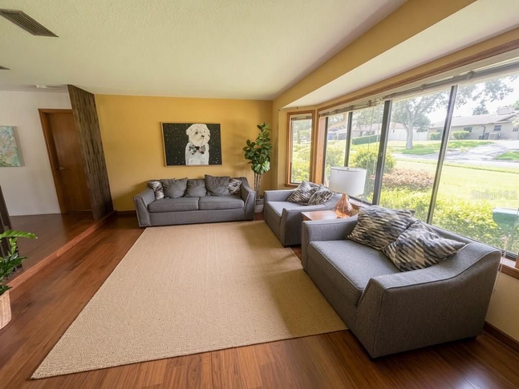 A living room features hardwood floors, a large area rug, grey furniture, and a bay window — 507 FERNWOOD DRIVE, ALTAMONTE SPRINGS, FL