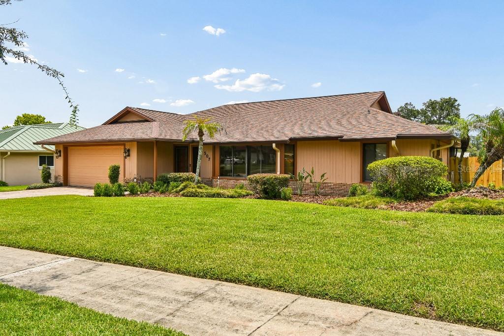 A single-story house with a brown shingled roof, tan siding, and a large front lawn — 507 FERNWOOD DRIVE, ALTAMONTE SPRINGS, FL