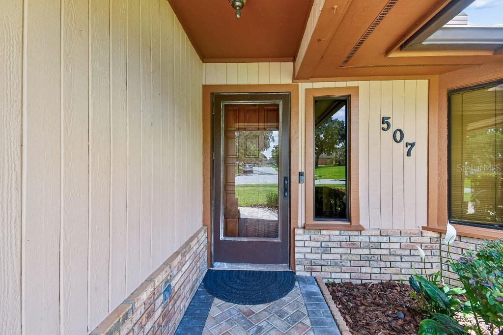 A front entryway features a glass-paneled door, brick accents, and vertical wood siding — 507 FERNWOOD DRIVE, ALTAMONTE SPRINGS, FL