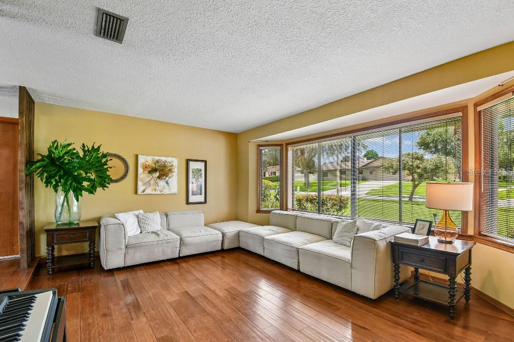 A living room with a large sectional sofa, hardwood floors, and a bay window — 507 FERNWOOD DRIVE, ALTAMONTE SPRINGS, FL
