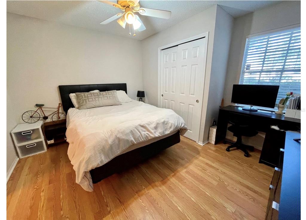A bedroom features a bed with a black headboard, a desk, and hardwood flooring — 3705 SW 27TH STREET UNIT 1113, GAINESVILLE, FL