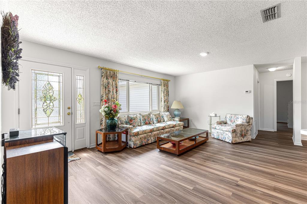 A living room features floral furniture, a glass coffee table, and wood-look flooring — 10956 SW 62ND TERRACE, OCALA, FL