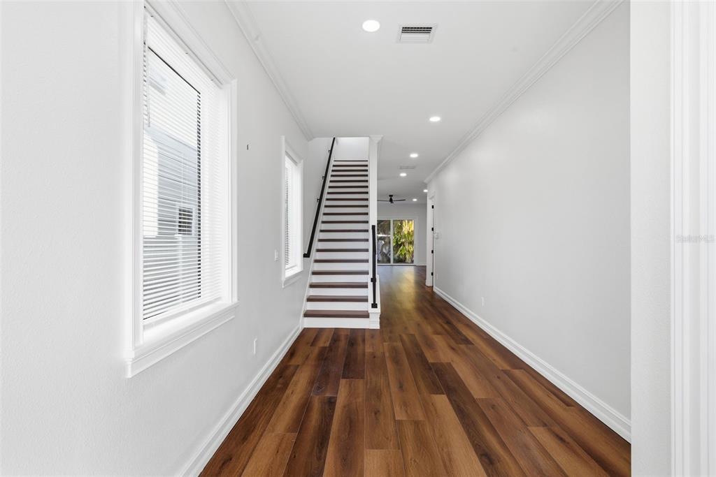 A hallway with wood-look flooring leads to a staircase and a view of the outdoors — 3829 71ST STREET N, ST PETERSBURG, FL