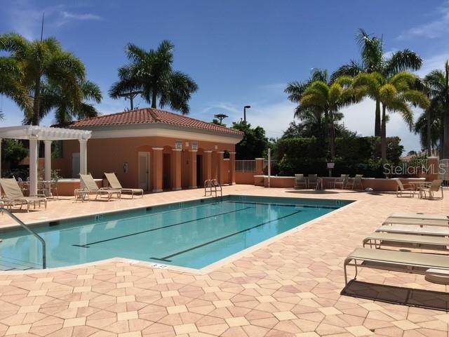 A swimming pool with lounge chairs sits in front of a clubhouse with palm trees — 3191 MATECUMBE KEY ROAD UNIT 303, PUNTA GORDA, FL