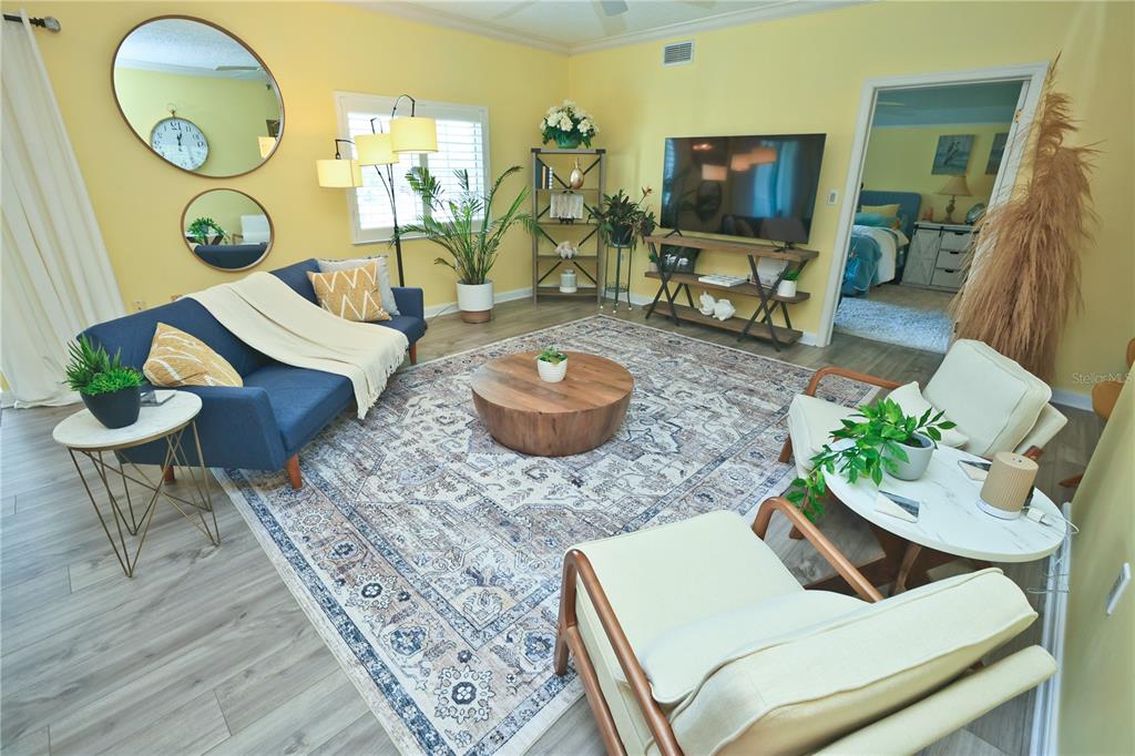 A living room features yellow walls, a blue sofa, two armchairs, and a large area rug — 3731 SARASOTA SQUARE BOULEVARD UNIT 101E, SARASOTA, FL