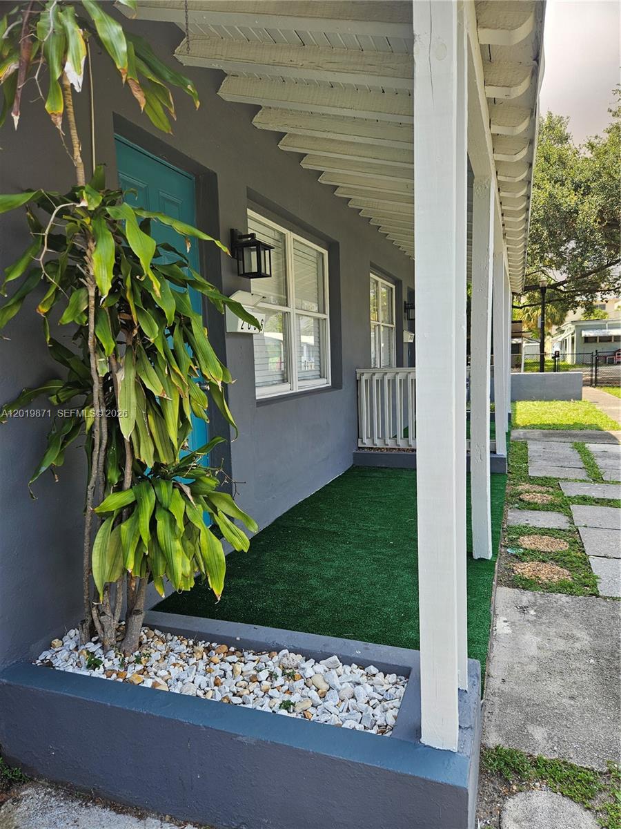 A grey exterior wall features a teal door, a window, and a covered porch area — 2030 Taylor St # 2030, Hollywood FL 33020, HOLLYWOOD, FL