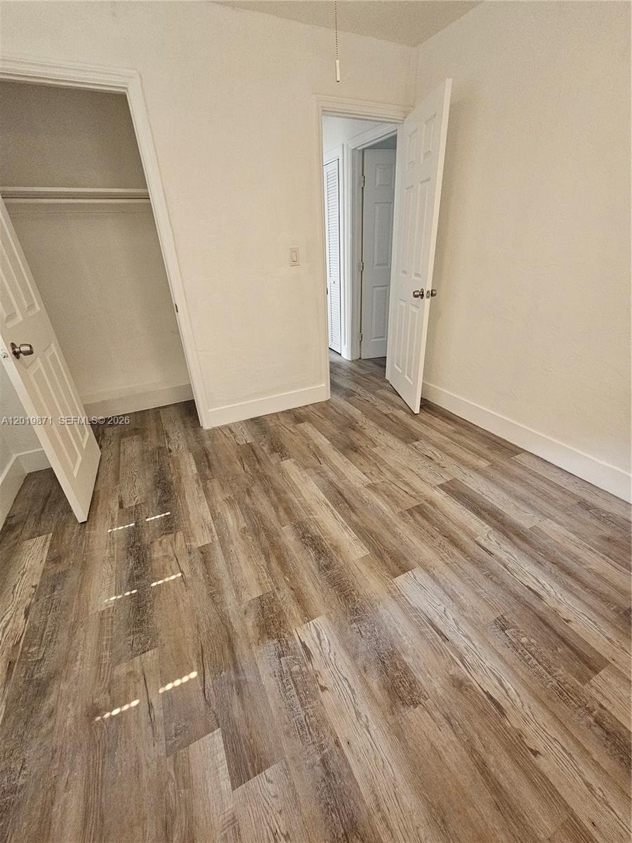 An empty room features wood-look flooring, a closet, and an open doorway leading to a hallway — 2030 Taylor St # 2030, Hollywood FL 33020, HOLLYWOOD, FL