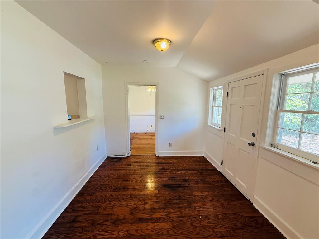 A room with dark hardwood floors, white walls, a ceiling light, and an exterior door — 745 NE 10TH AVENUE, GAINESVILLE, FL