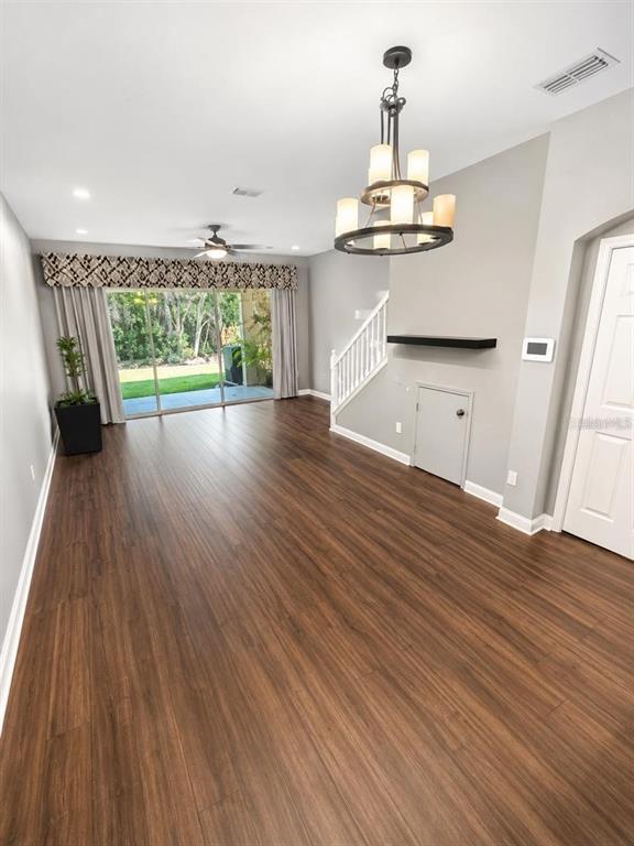 A living room features wood-look flooring, a chandelier, a ceiling fan, and sliding glass doors — 11253 WINDSOR PLACE CIRCLE, TAMPA, FL