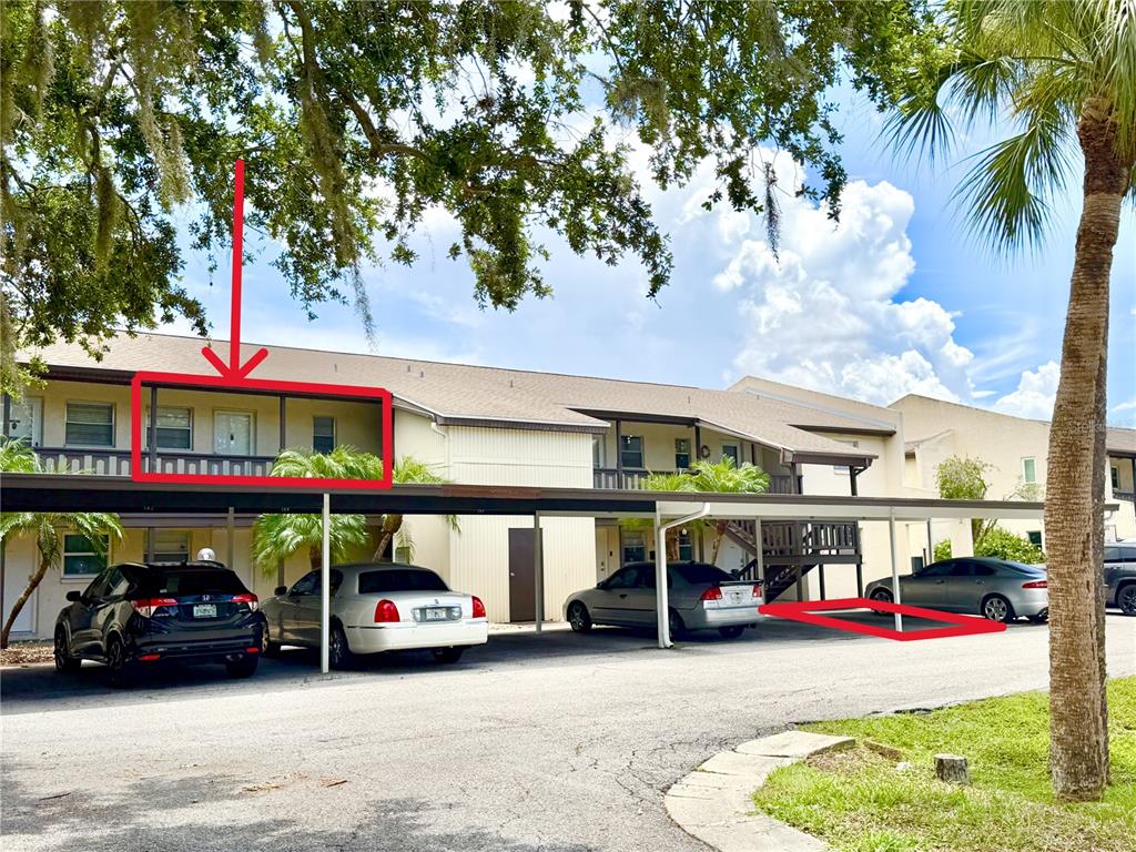 An exterior view of a two-story apartment building with covered parking spaces and a balcony — 4533 MARINE PARKWAY UNIT 204, NEW PORT RICHEY, FL